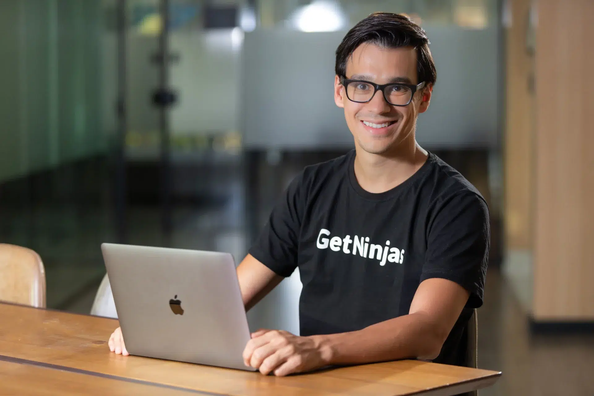 Foto do Eduardo L'Hotellier, CEO do GetNinjas, sentado em frente ao computadorure Capital na Headline, sorrindo enquanto